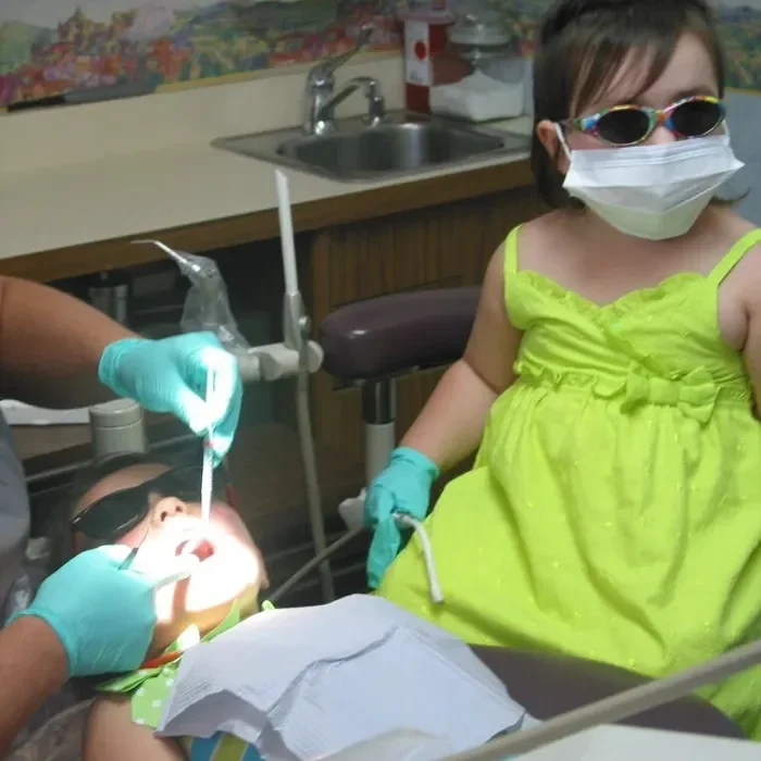 A pediatric patient in an exam chair while another pediatric patient sits nearby
